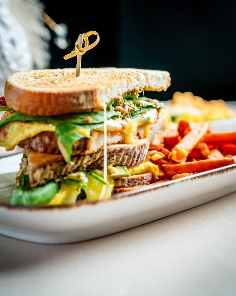 Grilled sandwich with cheese, lettuce, and fries on a white plate.